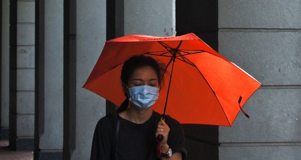 Moça com guarda-chuva e  máscara de proteção contra vírus